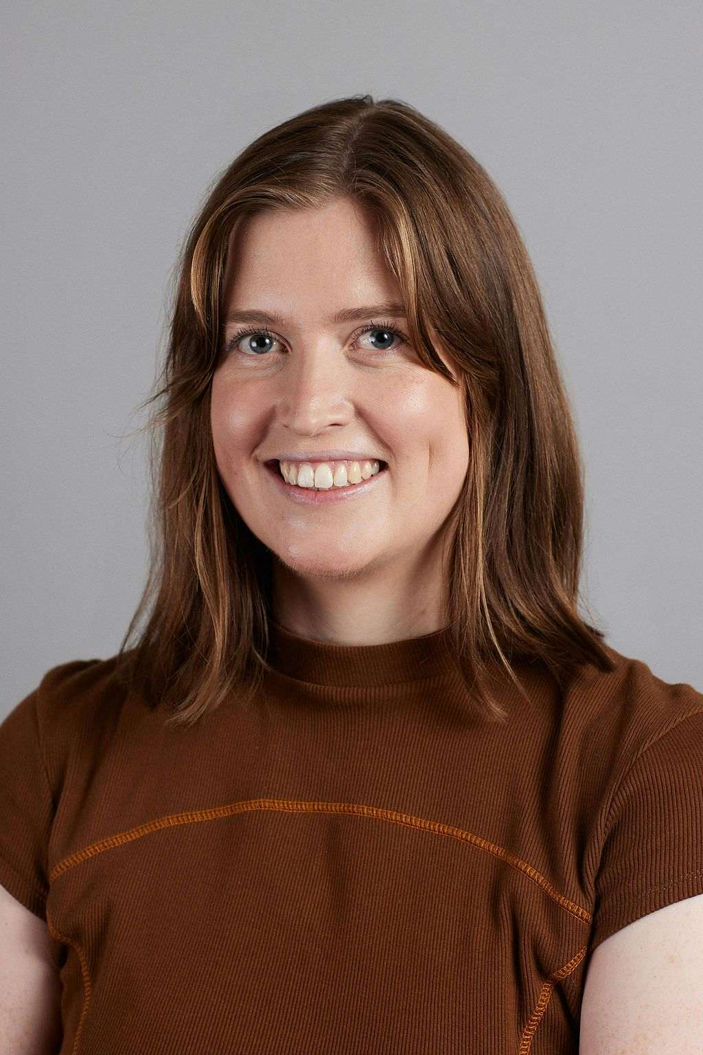 Headshot of Eleanor smiling and wearing a brown shirt.